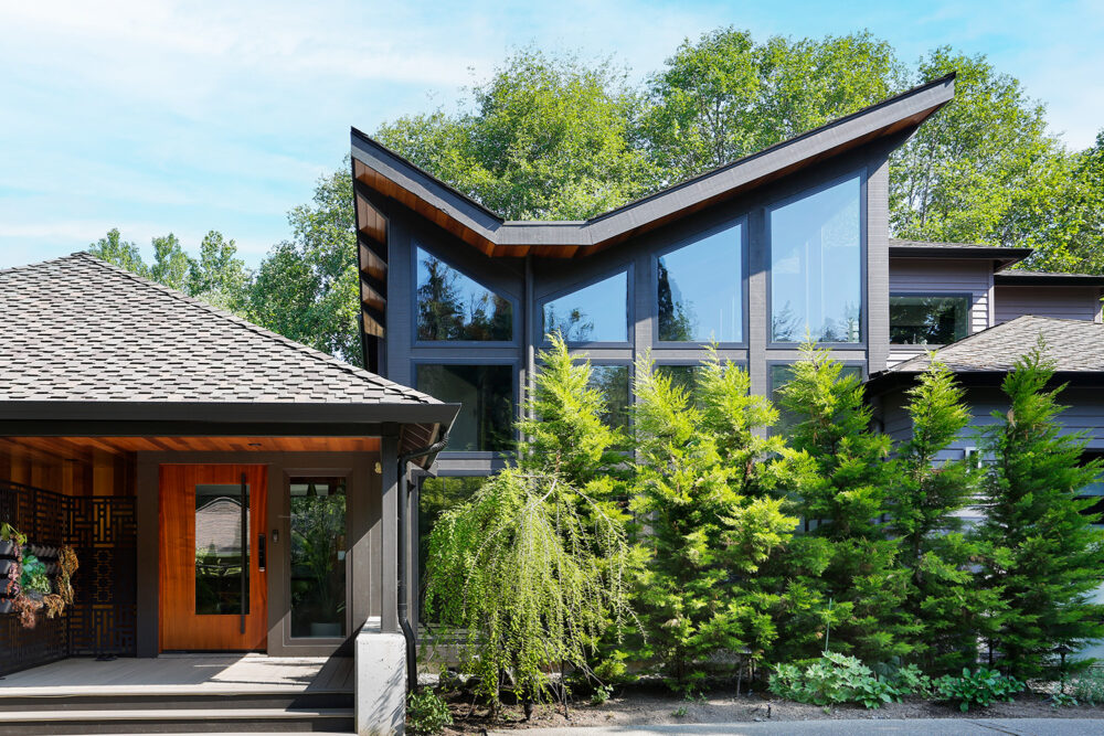 A direct view of the new addition glass wall and inverted gable roof from the driveway.