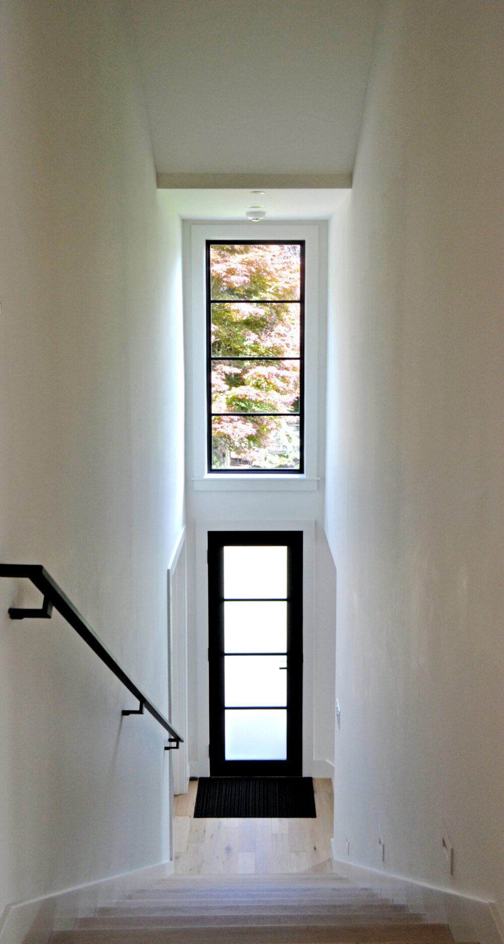 A hallway and staircase with tall ceiling and ample natural light.