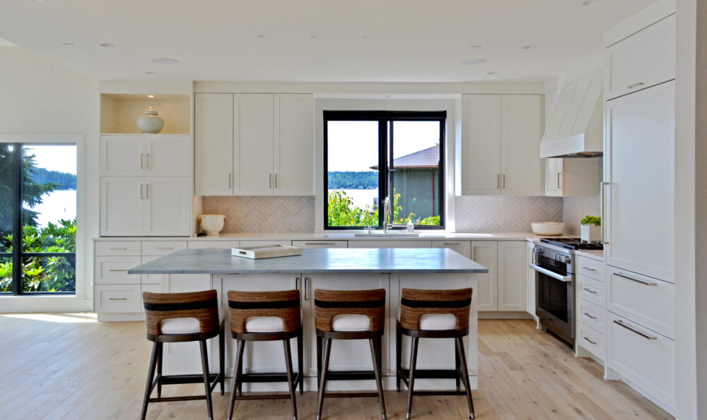The kitchen with large windows looking out at the water and greenery.