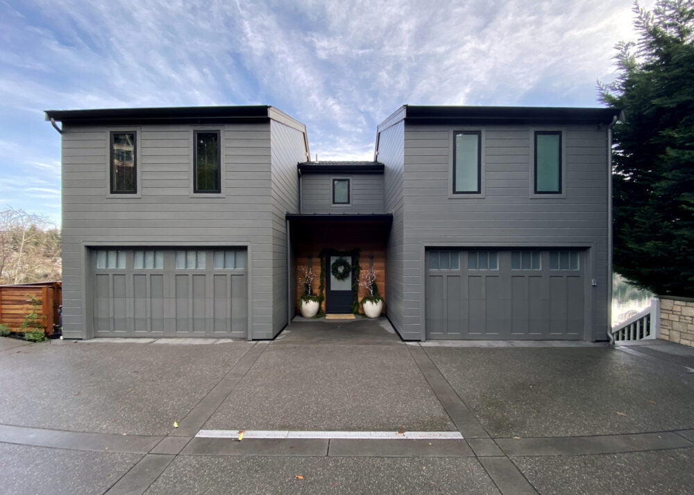 The front of the house with two garages on either side of the front entrance.