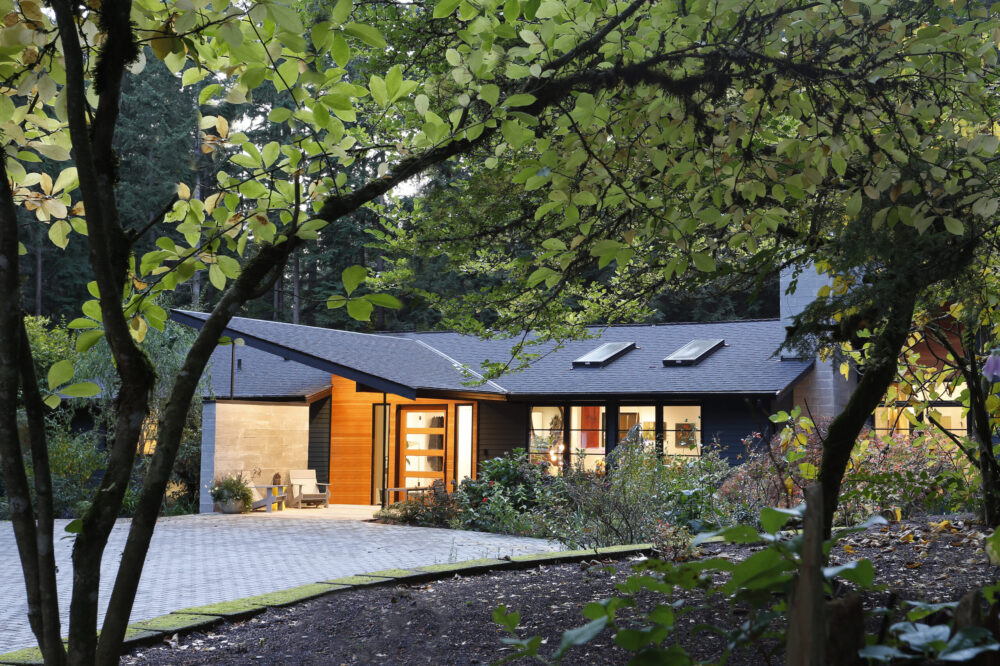 A view of the front entry porch behind some trees at night.